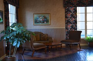 Una habitación con sofá, sillón y una planta grande en maceta.