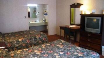Habitación de hotel con dos camas, un escritorio, un aparador, un televisor y un espejo.