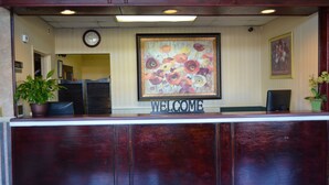 A reception desk with a 'WELCOME' sign, a clock, and a floral painting on the wall. - Travel Inn (Birmingham)