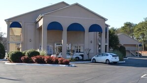 A building with a beige facade and blue arches, a parking lot, and a white car parked in front. - Travel Inn (Birmingham)