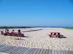 A beach with a wooden deck, red benches, and a picnic table.
