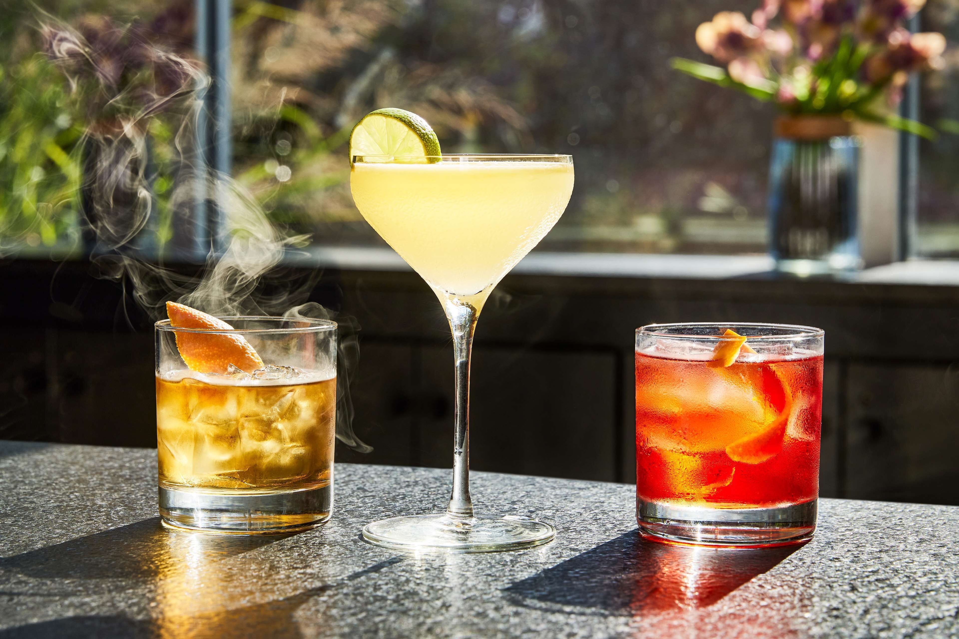 Three drinks on a table with a window view.