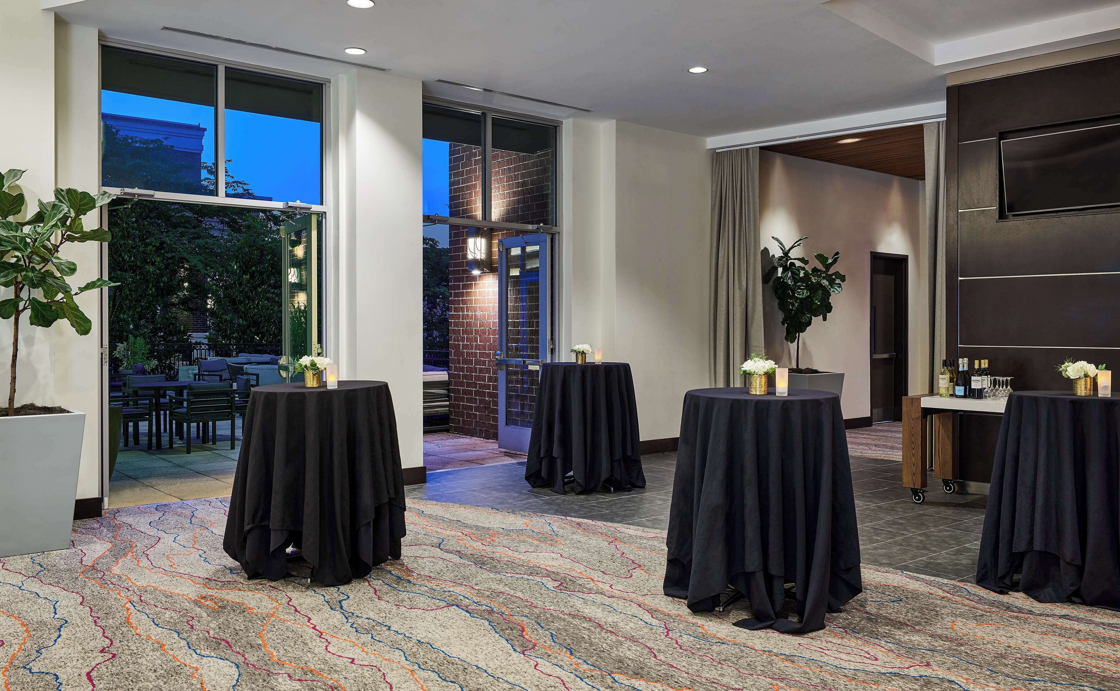 A conference room with multiple tables, large windows, and a view of the outdoors.