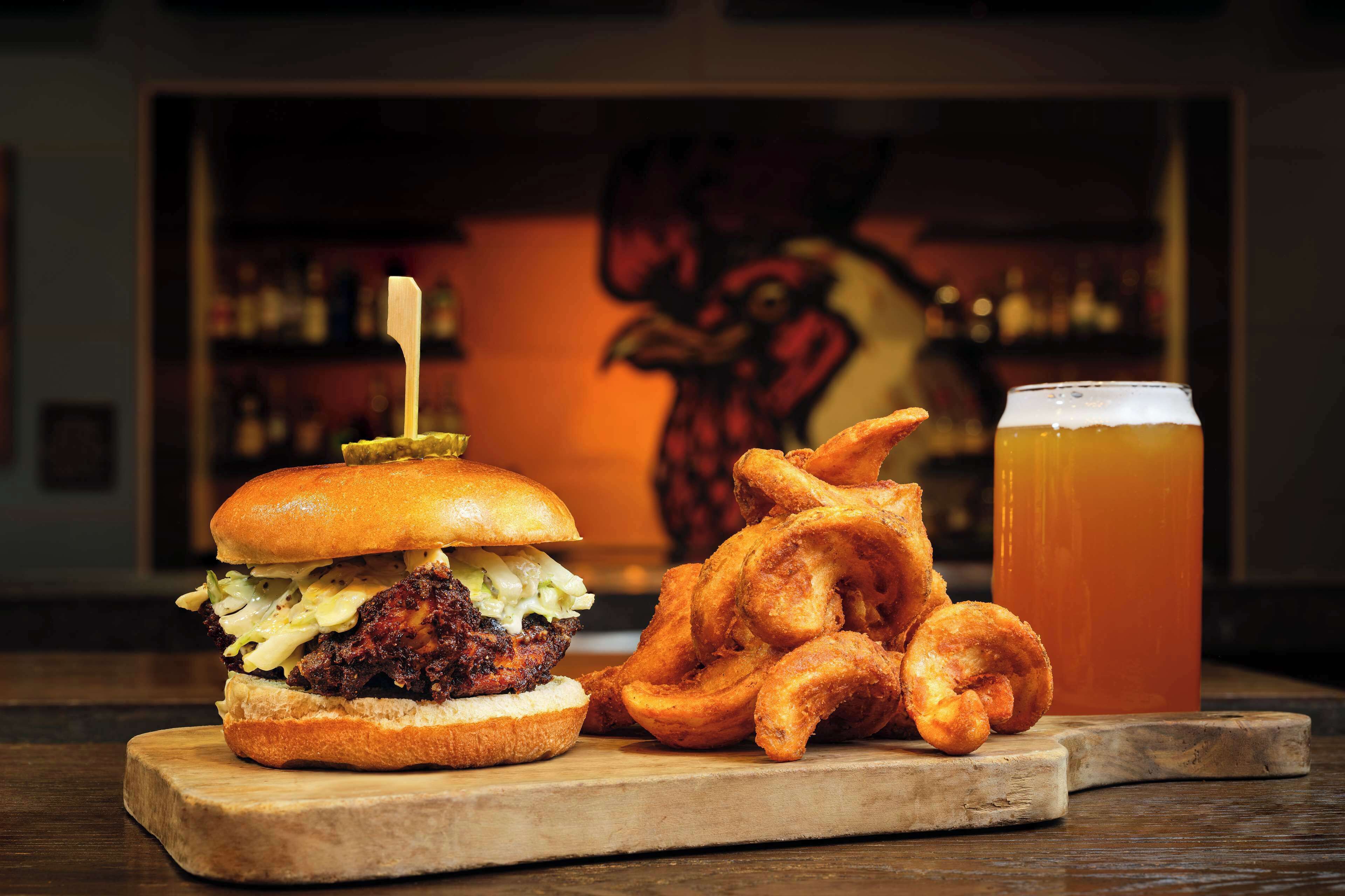Una hamburguesa, aros de cebolla y una cerveza en una tabla de madera.