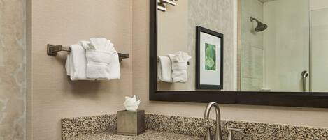 A bathroom with a granite countertop sink, a mirror, and two wall-mounted towel racks.