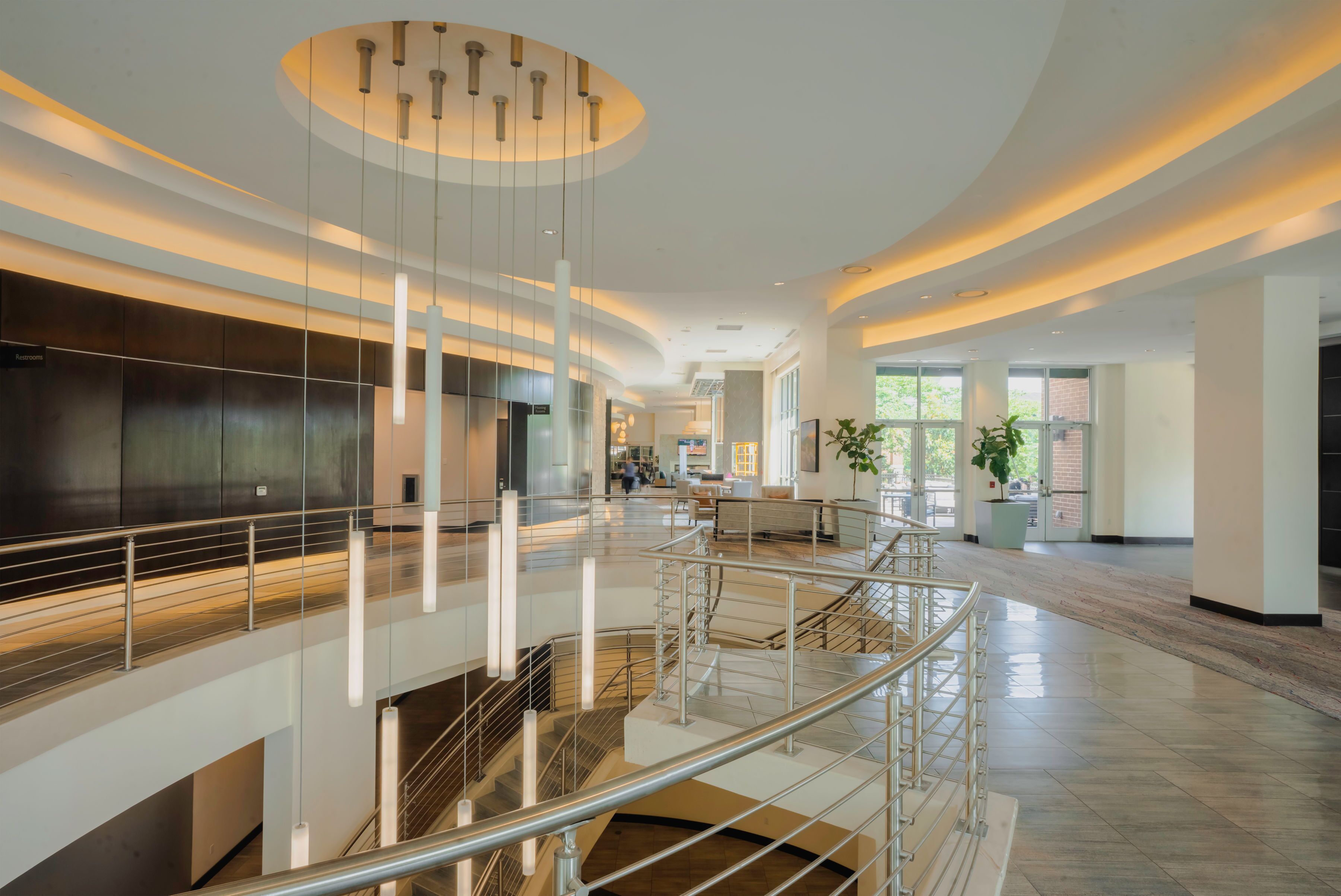A spacious interior with a central staircase, modern lighting, and a view of the outside.