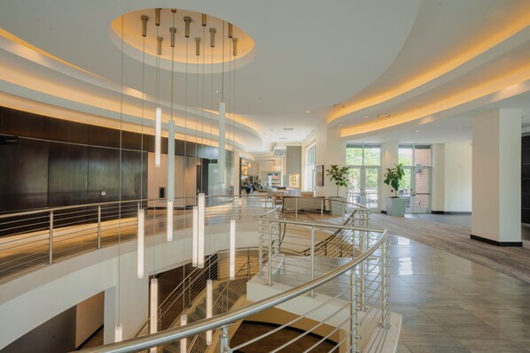 A spacious interior with a central staircase, modern lighting, and a view of the outside.
