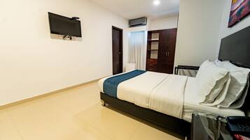 Quarto de hotel com cama, televisão na parede, guarda-roupa e ar condicionado.
