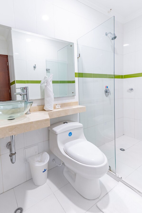 Un baño moderno con ducha de vidrio, inodoro blanco y lavamanos de vidrio.
