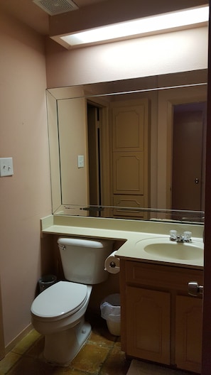 A bathroom with a toilet, sink, mirror, and cabinet.