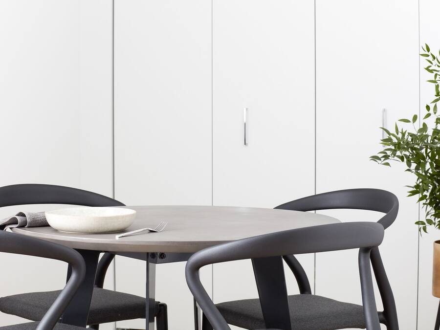 A dining area with a round table, two chairs, a bowl, a fork, and a potted plant.