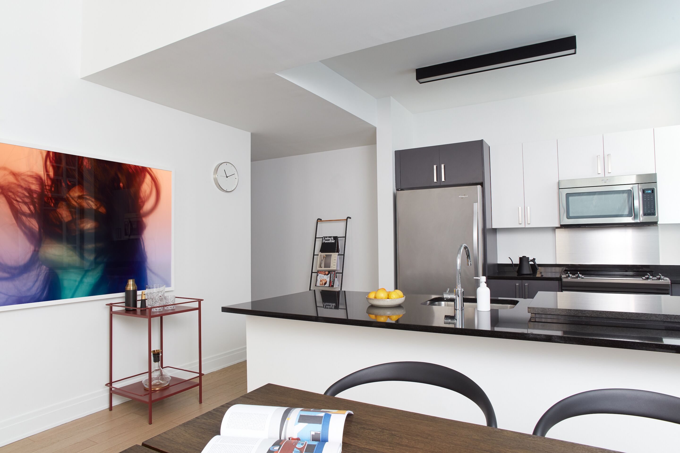 A modern kitchen with a black countertop, stainless steel appliances, and a white backsplash.
