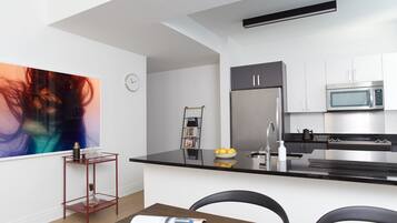 A modern kitchen with a black countertop, stainless steel appliances, and a white backsplash.