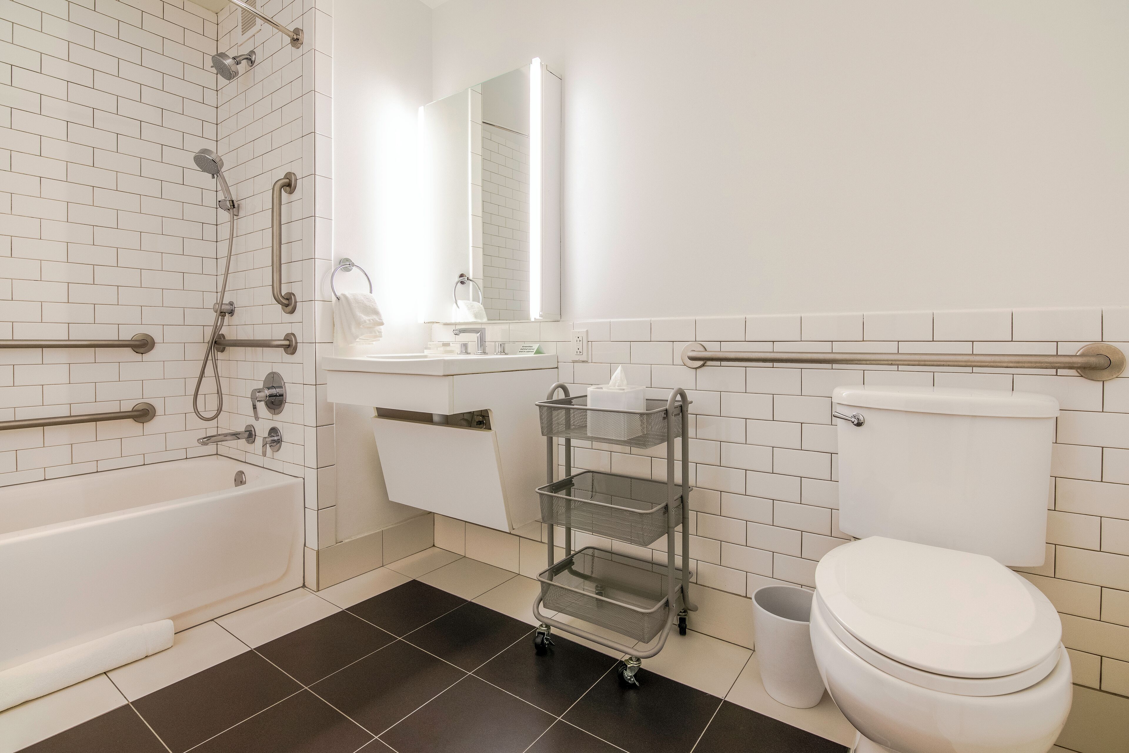 A modern bathroom with a bathtub, toilet, and a vanity with a mirror.