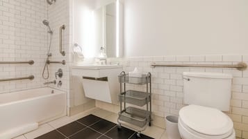 A modern bathroom with a bathtub, toilet, and a vanity with a mirror.