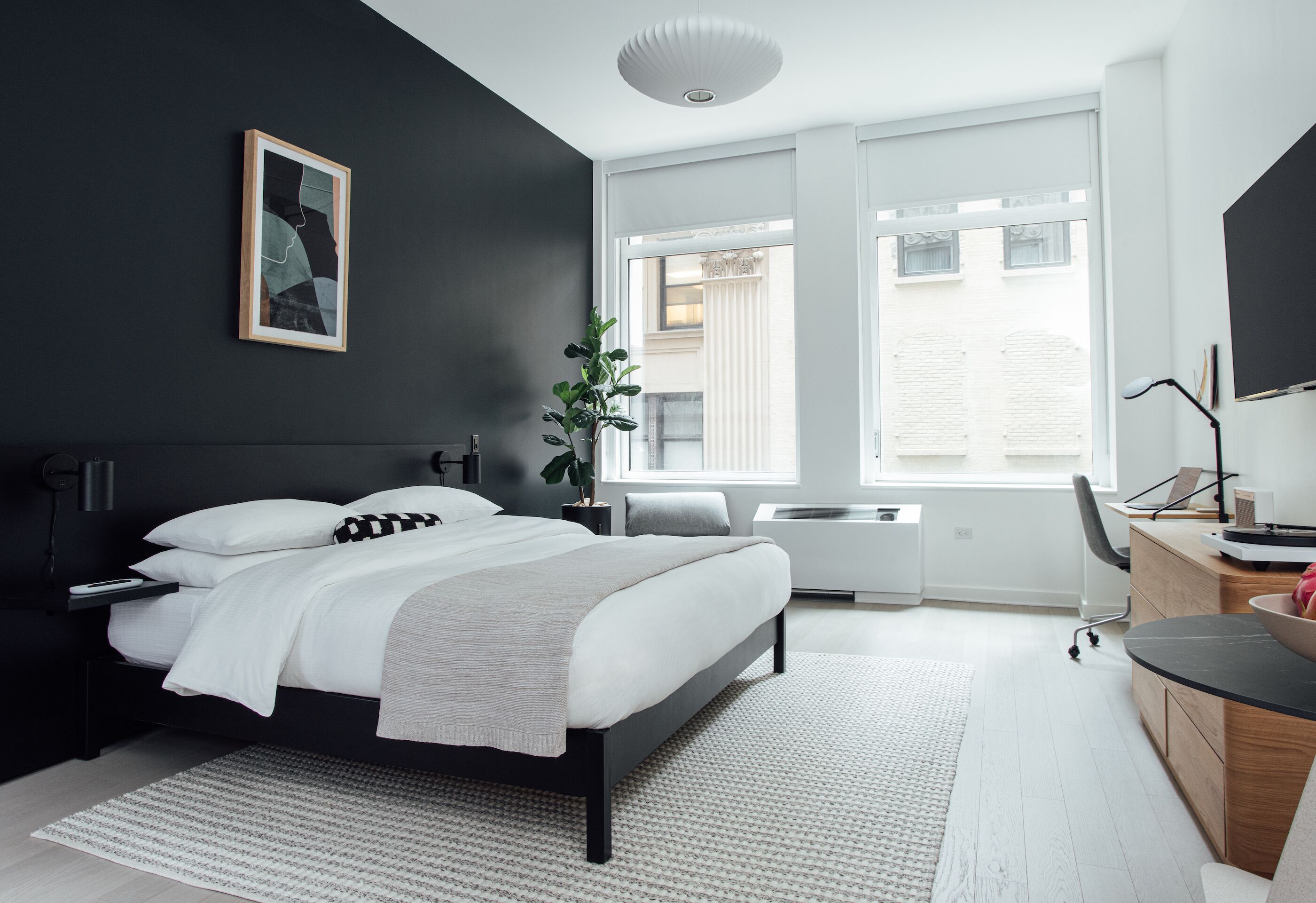 Une chambre moderne avec un lit, des tables de chevet, un bureau et une grande fenêtre.