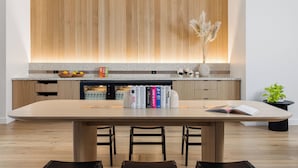 Una cocina moderna con armarios de madera, encimera de granito y comedor con mesa y sillas de madera.