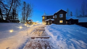 A snow-covered pathway leading to a house with a visible chimney and a porch. - Talkeetna Denali View Lodge and Cabins (Talkeetna)