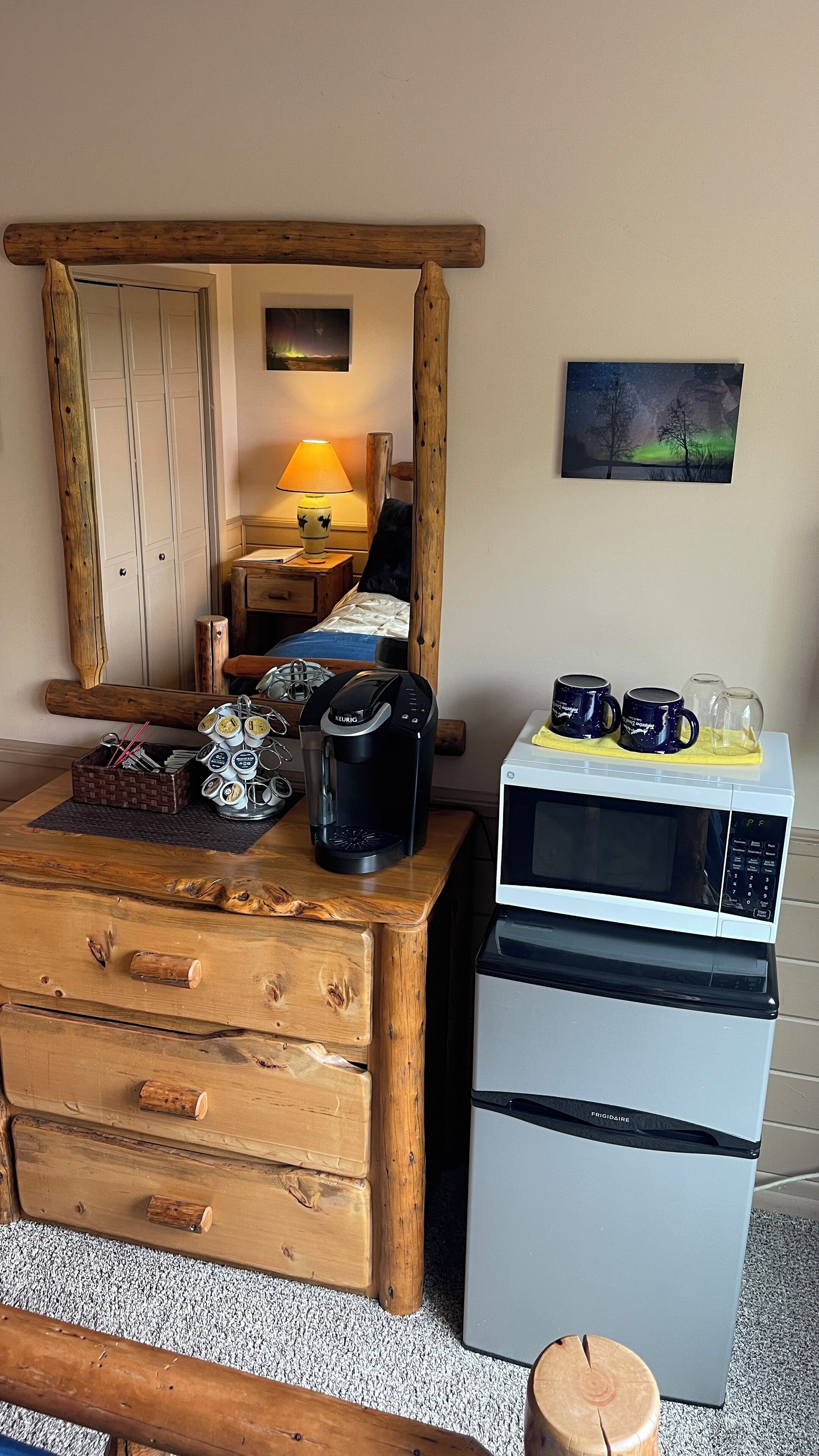 A kitchenette with a coffee maker, microwave, and a wooden cabinet with drawers.