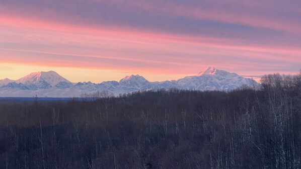 A mountainous landscape with snow-covered peaks and a forested foreground. - Talkeetna Denali View Lodge and Cabins (Talkeetna)