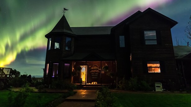 A two-story wooden building with a prominent tower and a sign advertising a lounge and restaurant. - Talkeetna Denali View Lodge and Cabins (Talkeetna)