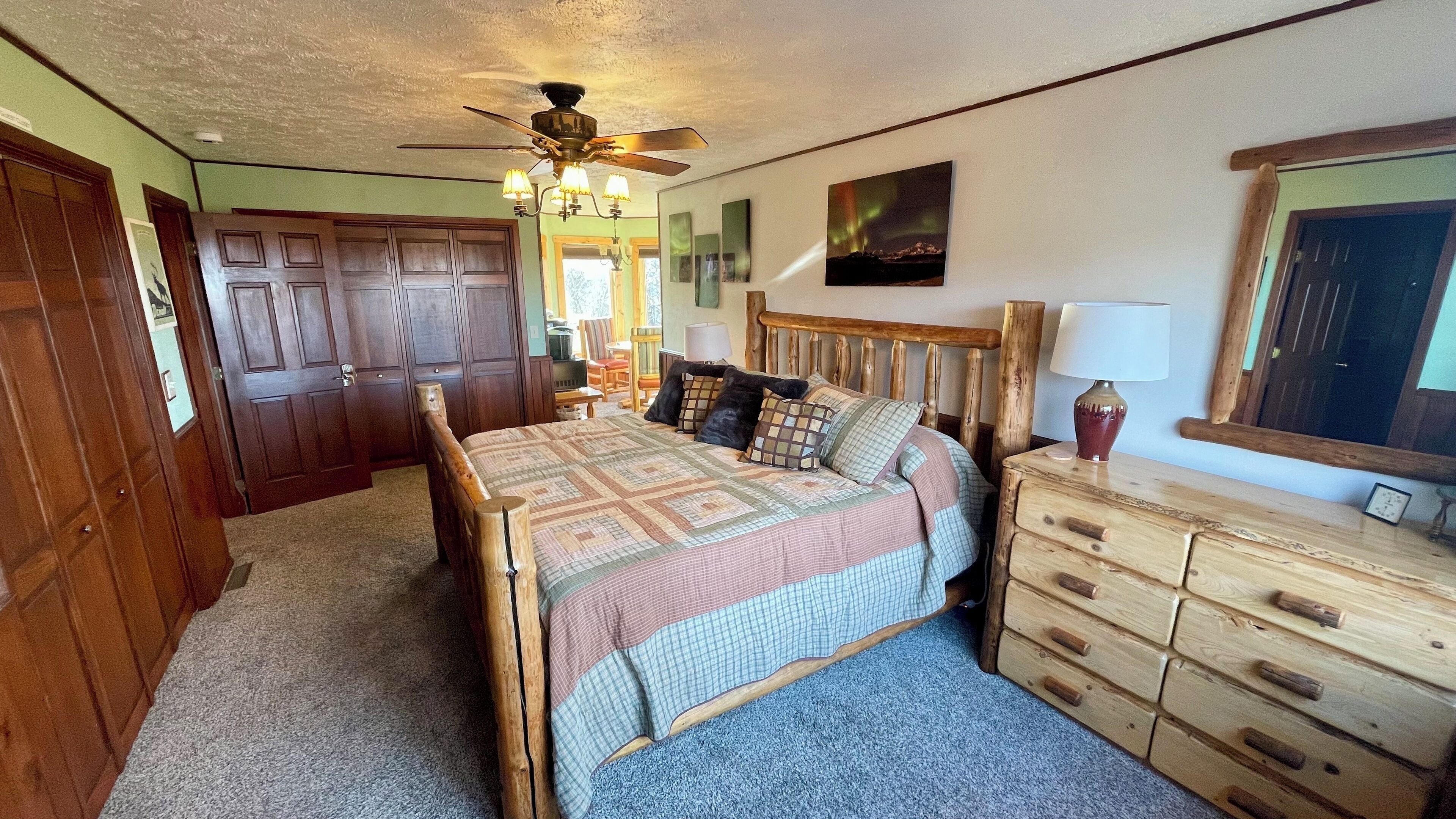 A bedroom with a wooden bed, a ceiling fan, a dresser, and a mirror.
