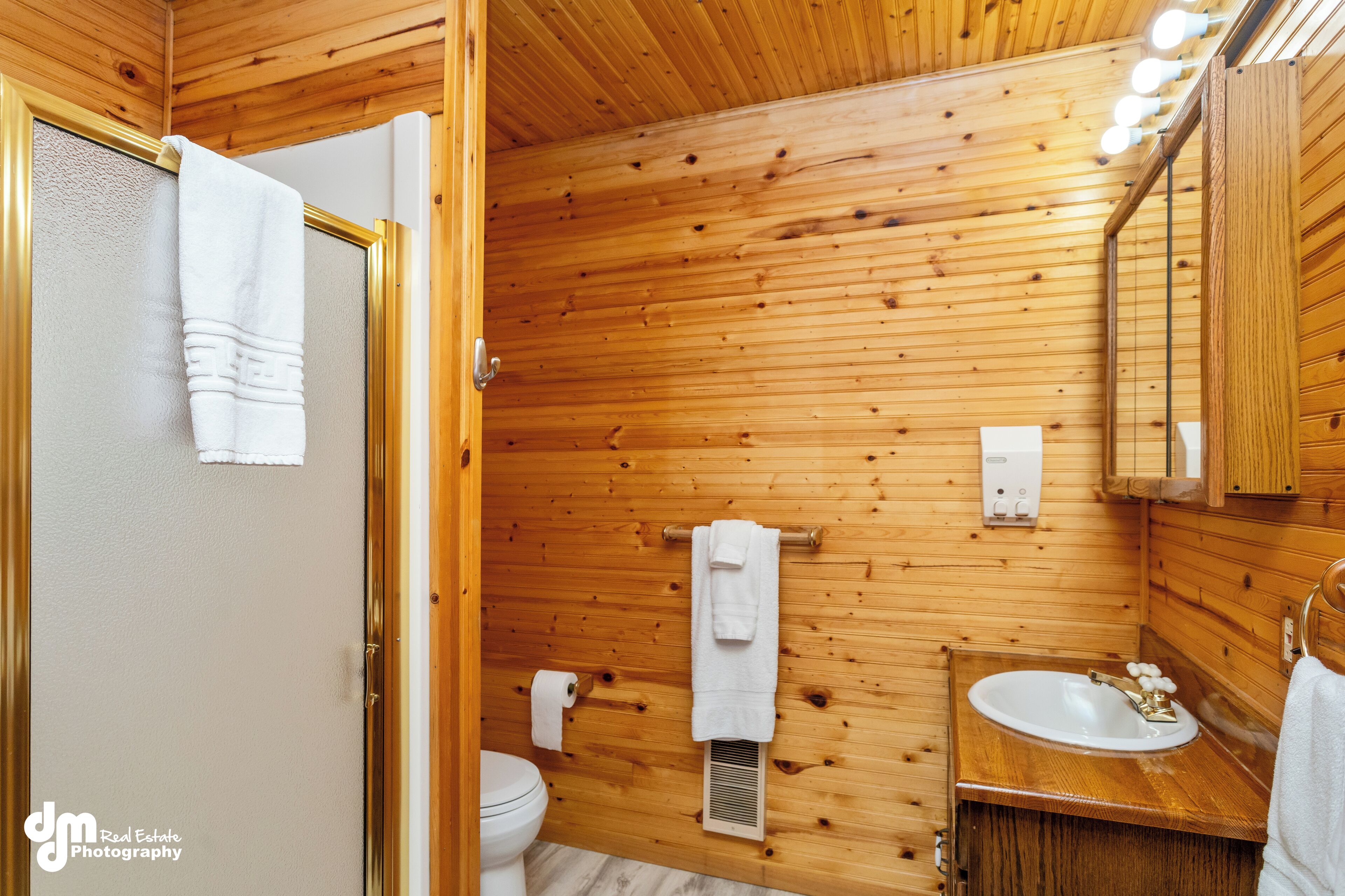 A wooden-paneled bathroom with a sink, mirror, and towel rack.