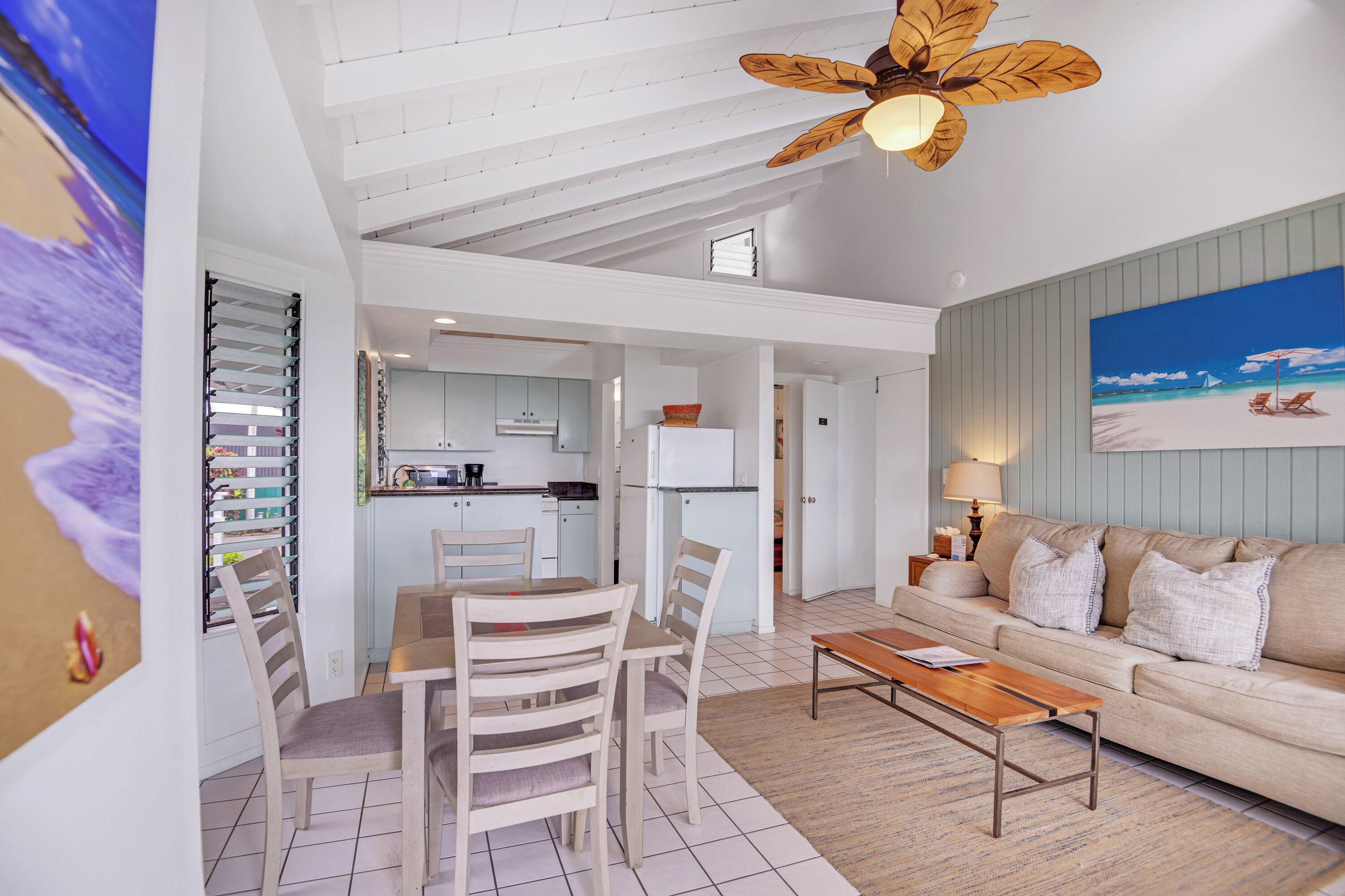 A spacious living area with a dining table and chairs, a sofa, and a ceiling fan.