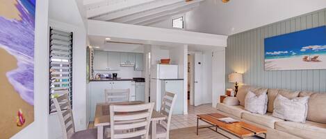 A spacious living area with a dining table and chairs, a sofa, and a ceiling fan.