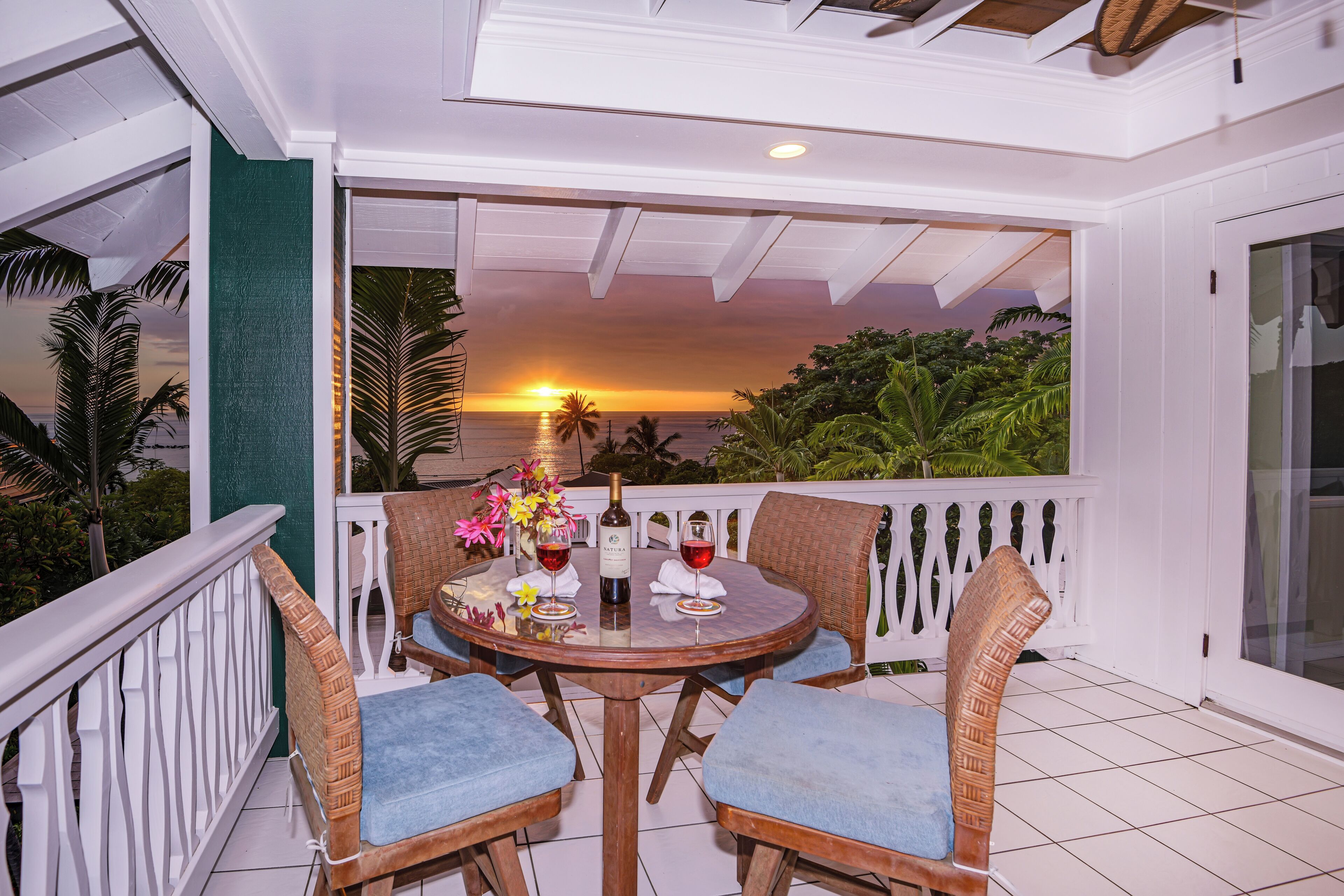 Un balcon avec une table dressée pour deux personnes, offrant une vue imprenable sur le coucher du soleil.
