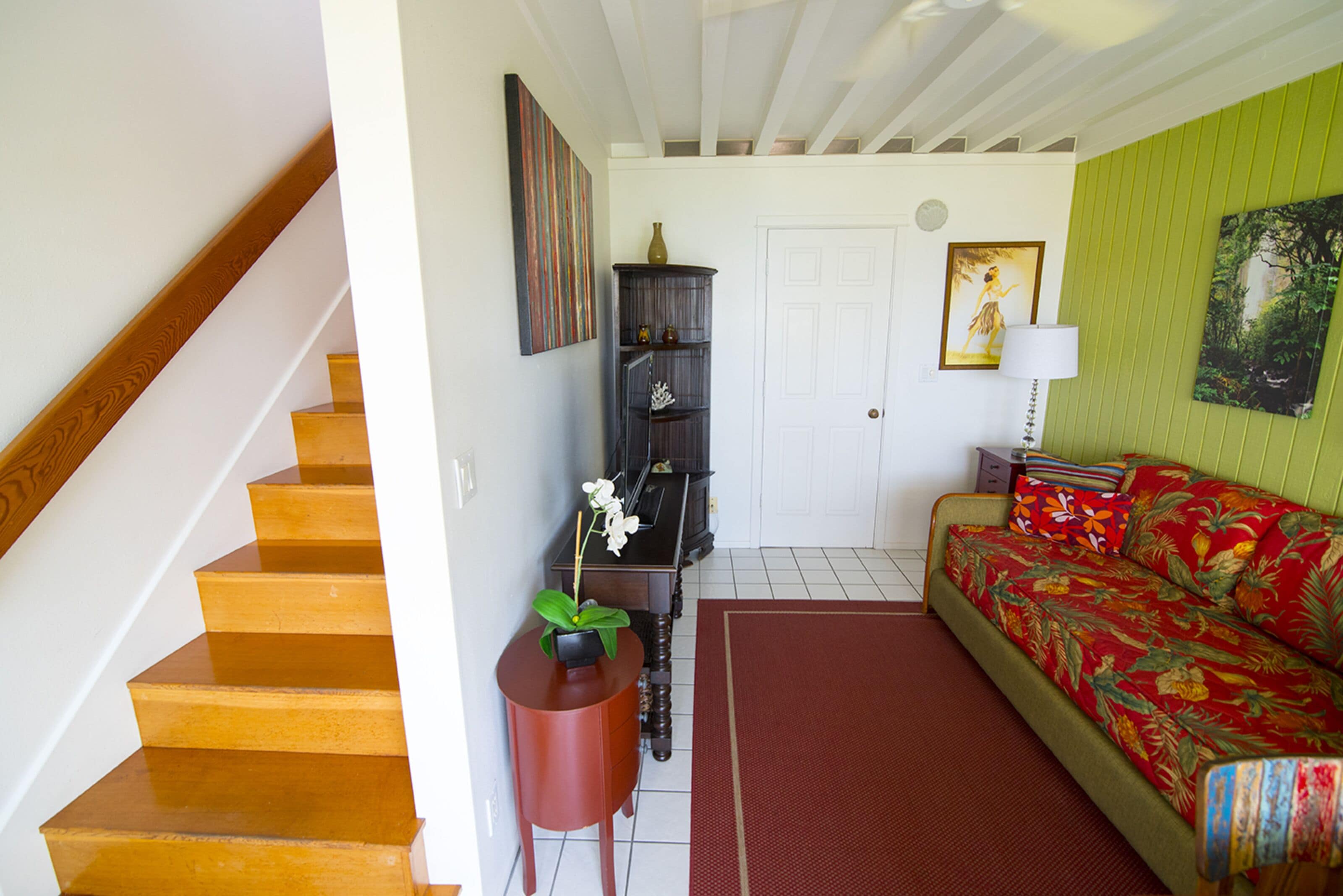 Escadaria que leva a um quarto com sofá, mesinha com planta, armário e porta.