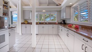 Una cocina amplia con armarios blancos, encimera de granito y ventana con persianas.