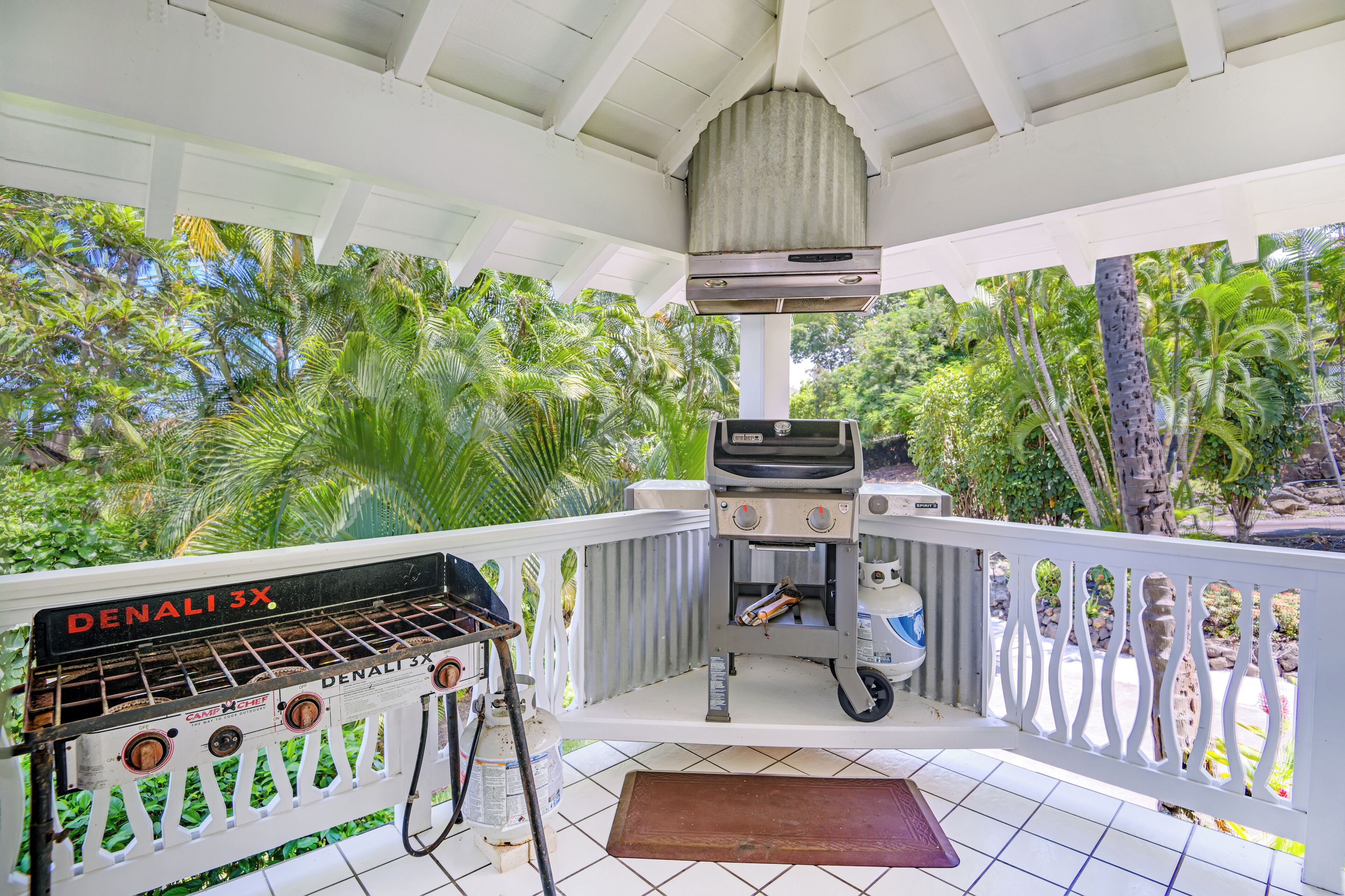 A covered outdoor area with a barbecue grill, a gas can, and a water dispenser.