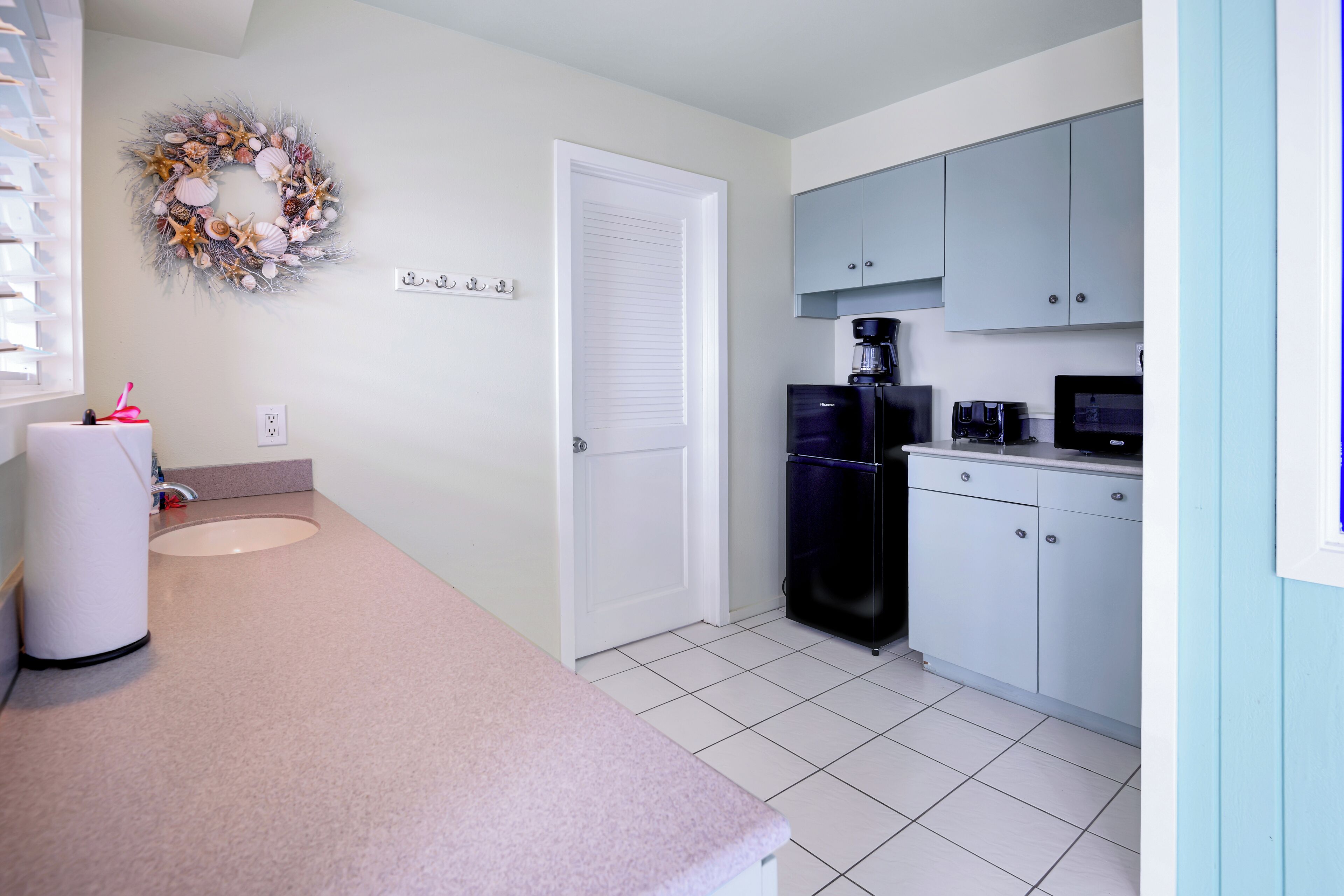 A kitchen with white cabinets, a black refrigerator, a coffee maker, and a microwave.