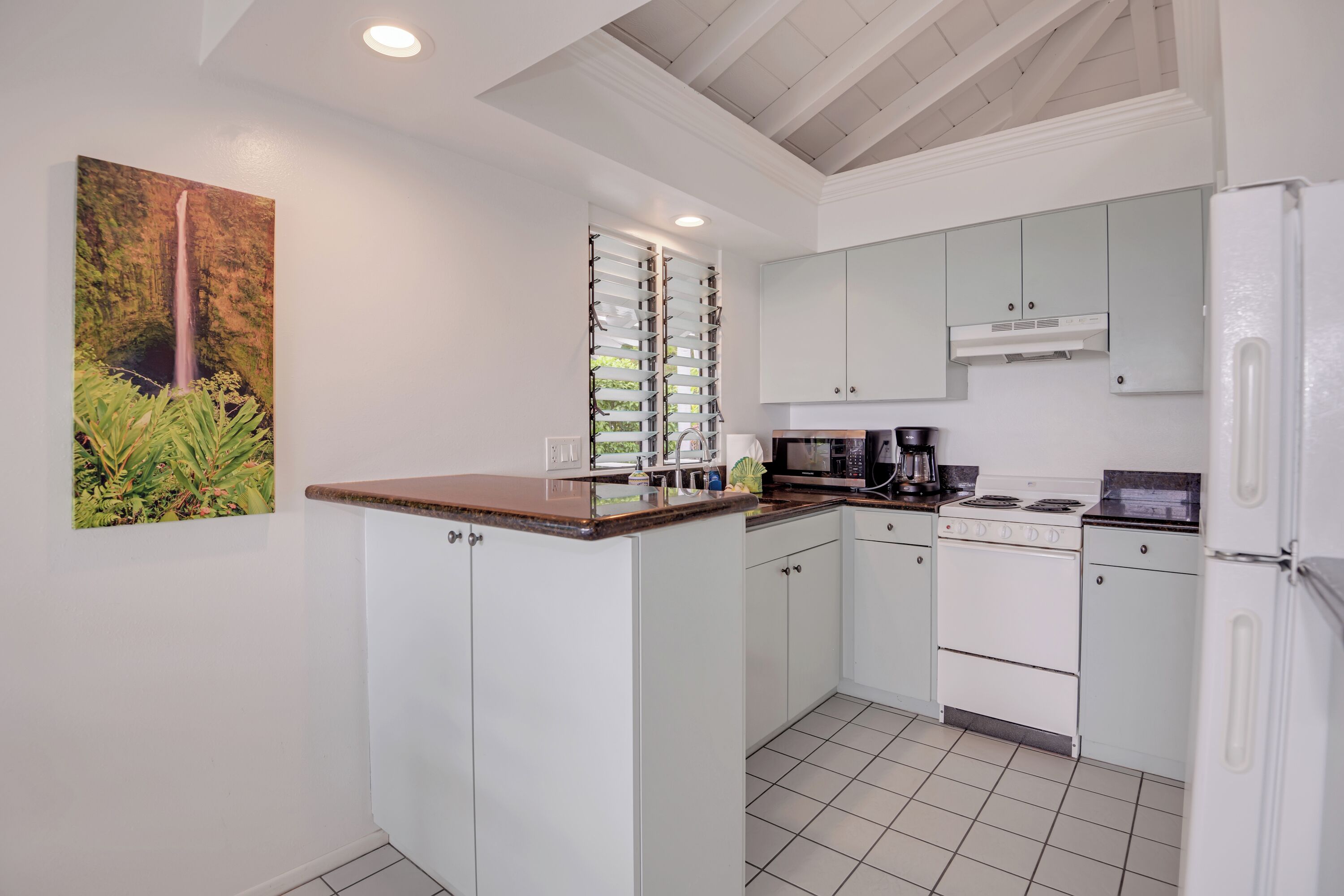 Una cocina compacta con armarios blancos, encimera de madera, estufa integrada y refrigerador.