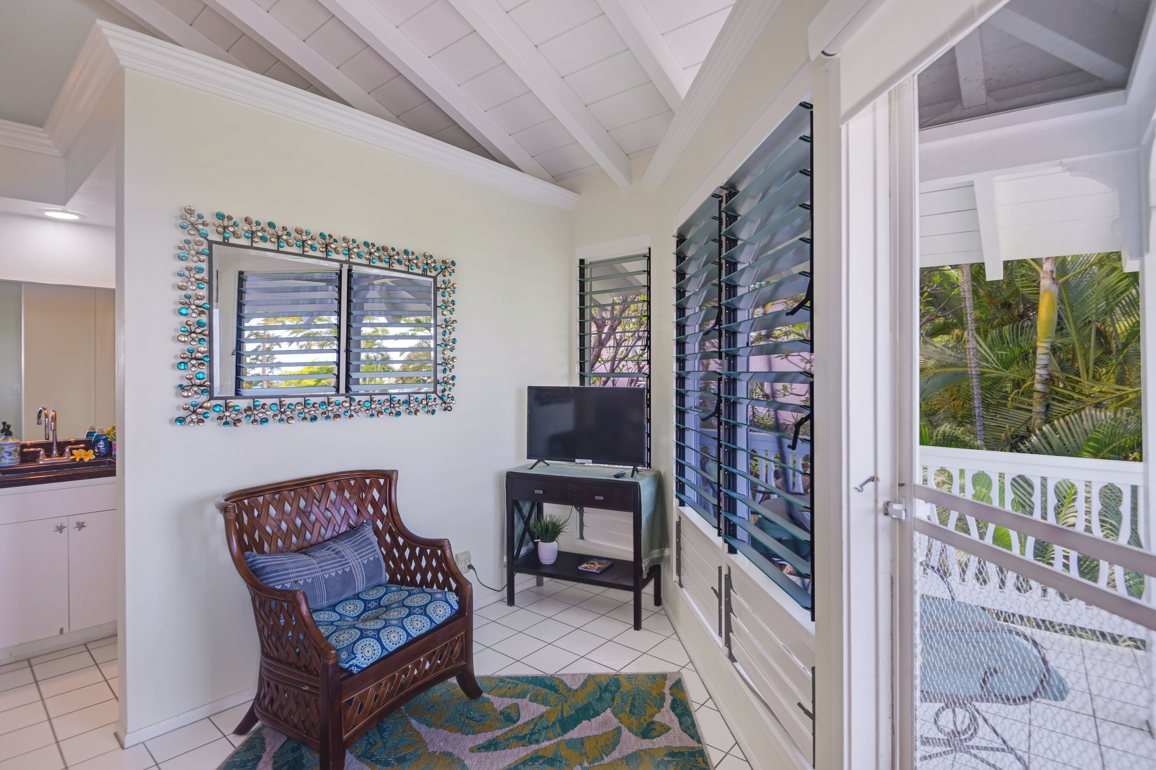 A room with a wooden chair, a small table with a TV, and a window with decorative shutters.