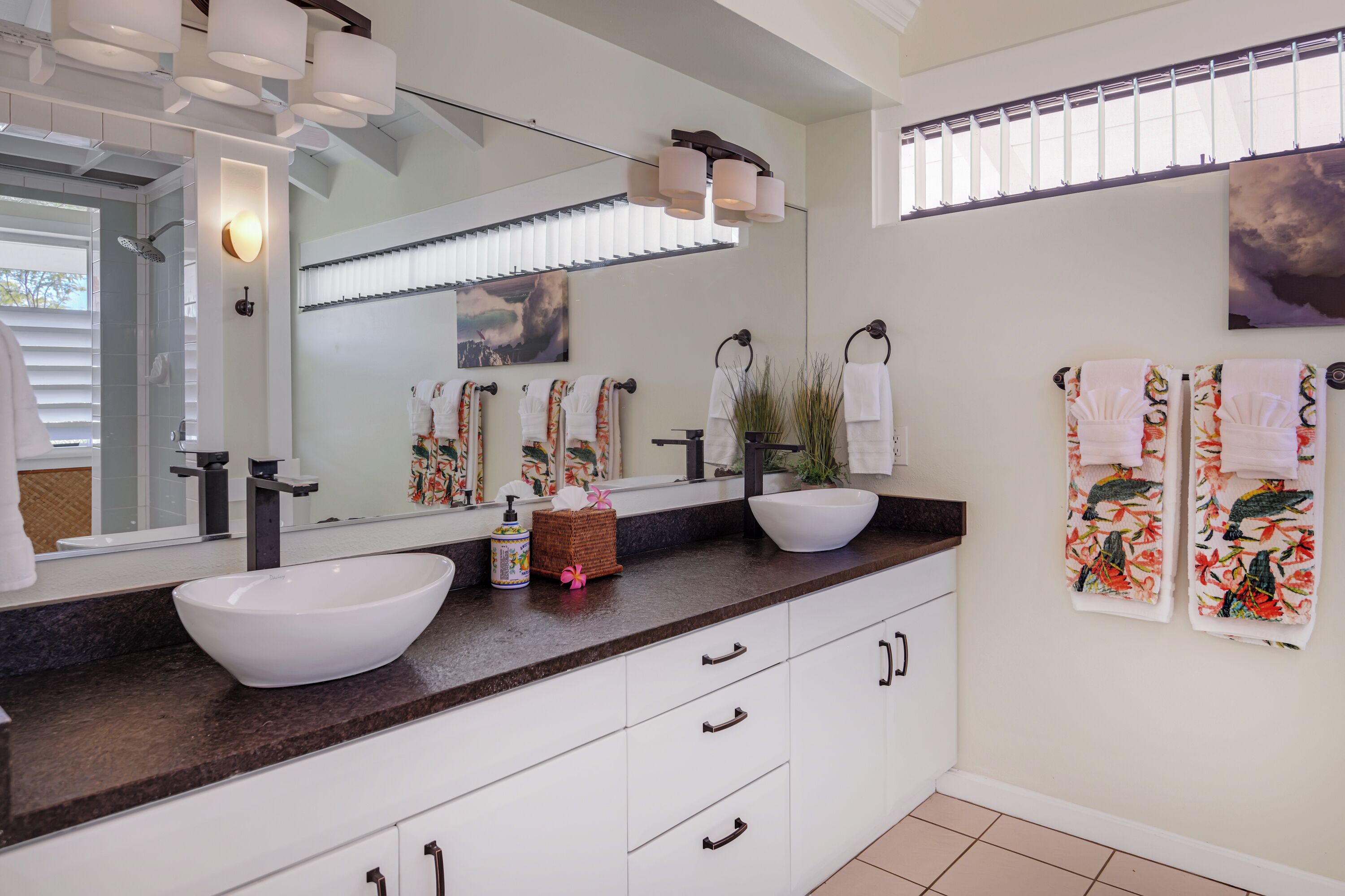Une salle de bain moderne avec un grand miroir, deux lavabos, une douche et un meuble-lavabo avec des tiroirs.