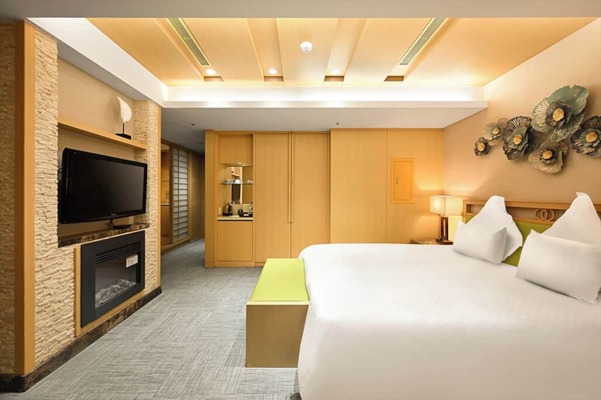 A hotel room with a bed, a television, a desk, and a wardrobe.