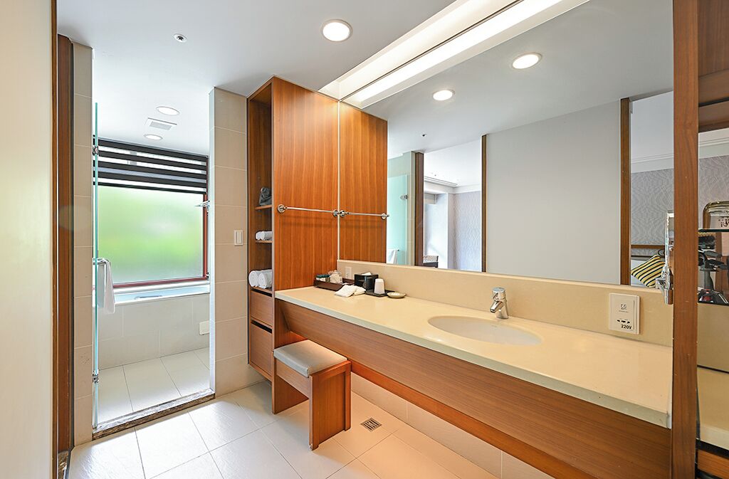A modern bathroom with a large mirror, wooden vanity, and a glass shower enclosure.