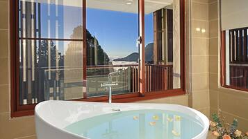 A large freestanding bathtub in a bathroom with a view of a snowy mountain range through a large window.