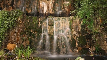 A waterfall cascading over a rocky cliff surrounded by lush greenery.