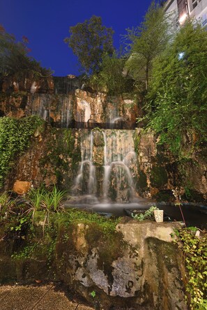 A waterfall cascading over a rocky cliff surrounded by lush greenery. - Alishan Hotel (Alishan)