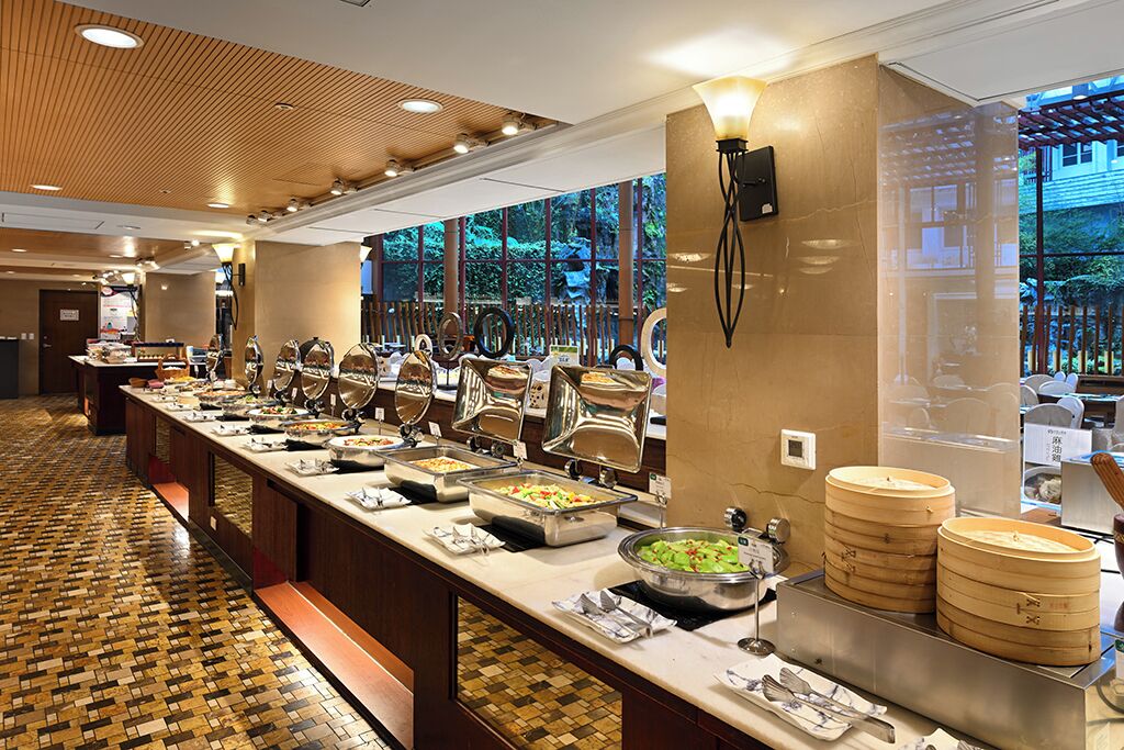 A buffet setup with various food stations and a wooden floor pattern.
