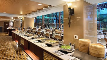 A buffet setup with various food stations and a wooden floor pattern.