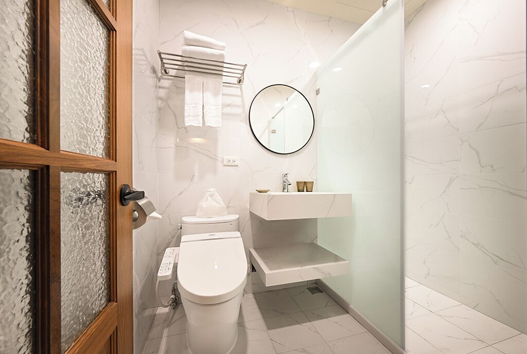 A modern bathroom with a toilet, a sink, a mirror, and a glass shower enclosure.