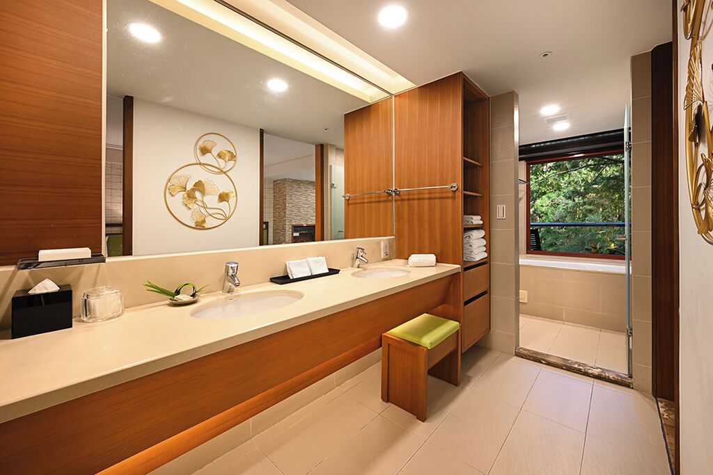 Une salle de bain moderne avec un grand miroir, deux vasques, un meuble-lavabo en bois et un banc.