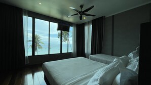 Une chambre d’hôtel avec deux lits, un ventilateur de plafond et vue sur l’océan.