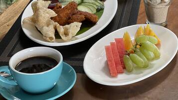 A table with a meal consisting of rice, chicken, peanuts, cucumber slices, and a glass of orange juice.