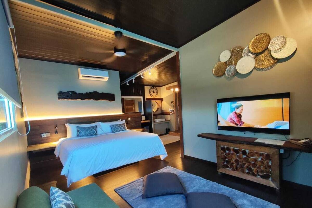 A modern bedroom with a large bed, a TV, and a cozy seating area.