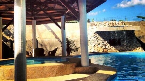 Un espace piscine abrité, avec des murs en pierre et un ciel d’un bleu limpide.